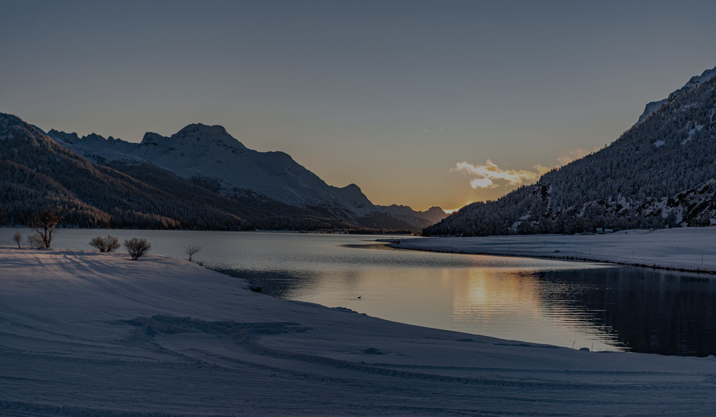 Silvaplanersee im Engadin bei Sonnenuntergang, verschneite Berge spiegeln sich im Wasser